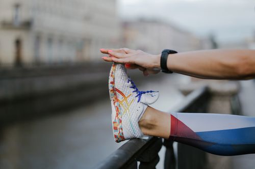 Free A person stretching their leg with colorful shoes by a canal in an urban setting. Stock Photo