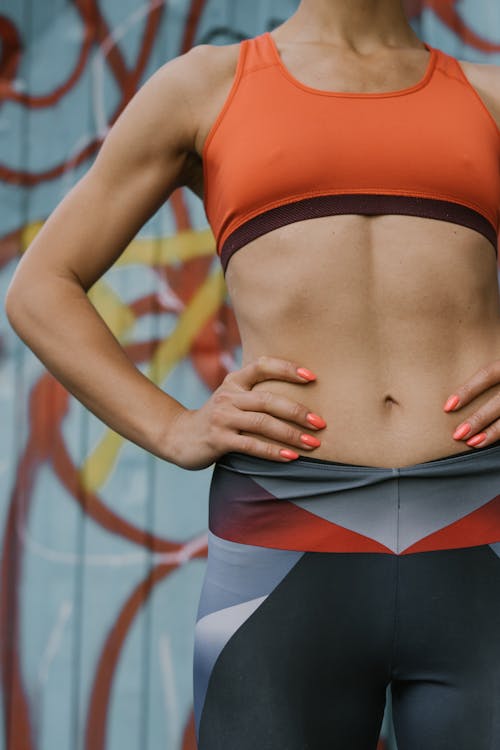 Free A Woman in Orange Sports Bra with Her Hands on Her Waist Stock Photo