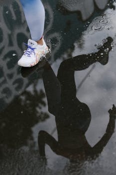 Dynamic shot of a runner's reflection and splash in a puddle, capturing movement.