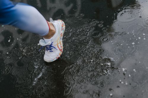 Free Close-up of a runner's shoe splashing through a puddle on a rainy day. Stock Photo