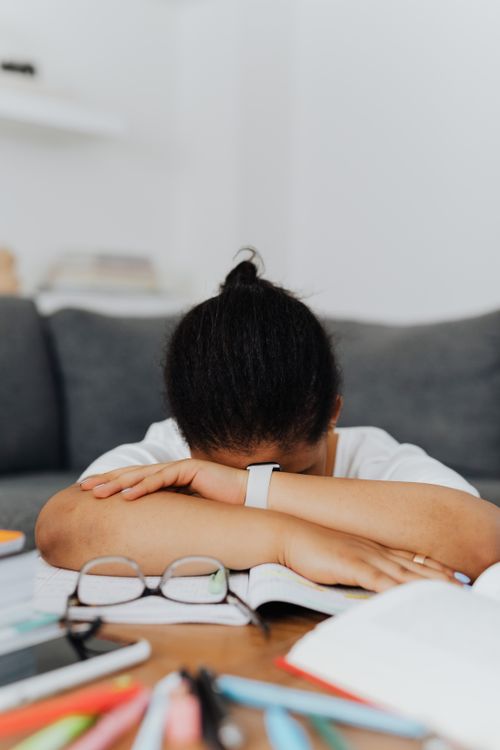 Free A tired student resting on a study table amidst books, embodying study fatigue. Stock Photo