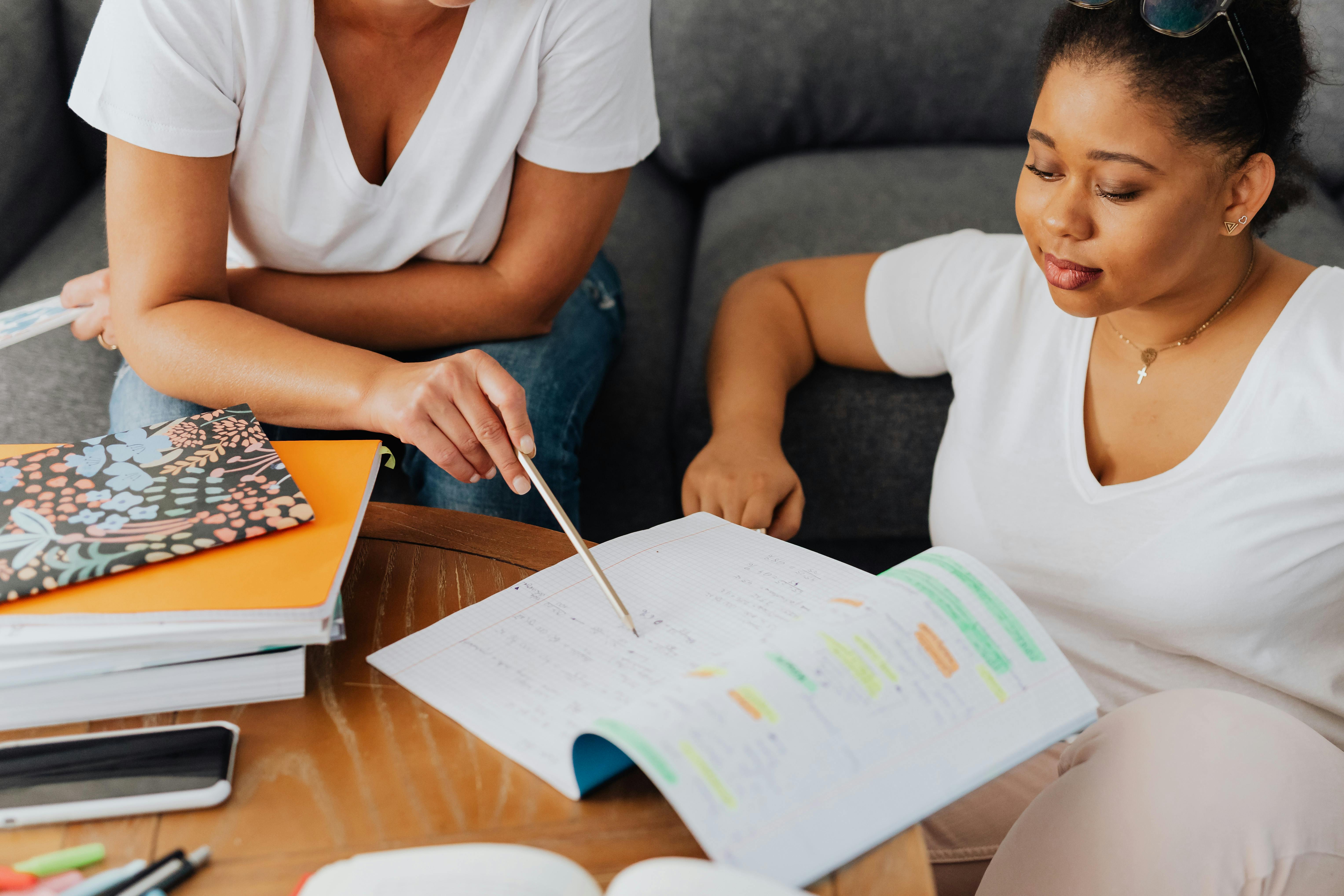 Öğrenci ve özel ders öğretmeni çalışma seansında notlar ve kırtasiye ile meşgul.