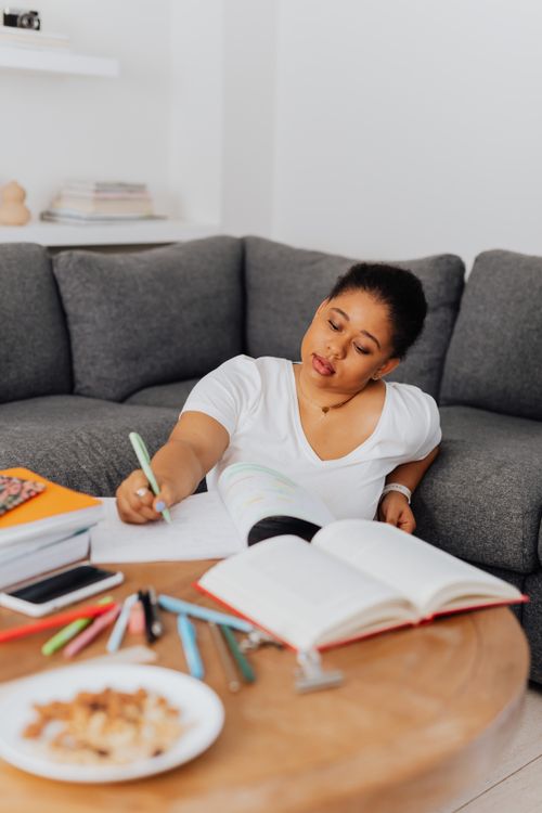 Free Young woman wearing white shirt studying at home with a notebook and pen. Stock Photo
