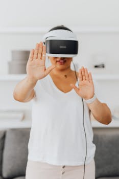 Adult woman using VR headset indoors, experiencing virtual reality with interactive gestures.
