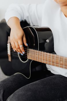 A close-up shot of a hand strumming an acoustic guitar, focused on the strings.