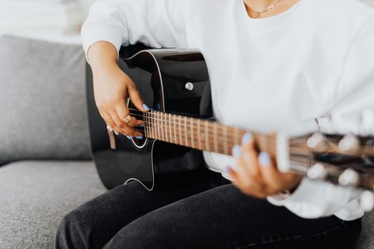 Person playing an acoustic guitar indoors, focusing on the fretboard and hands.. person, playing, acoustic