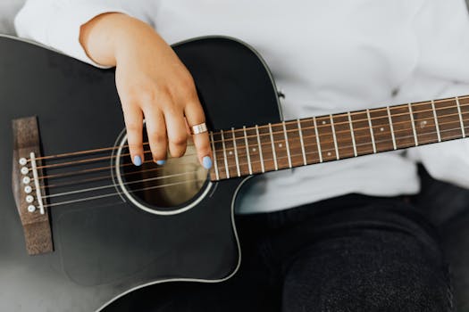 A close-up view of a person in white sleeves playing an acoustic guitar, highlighting musical expression.
