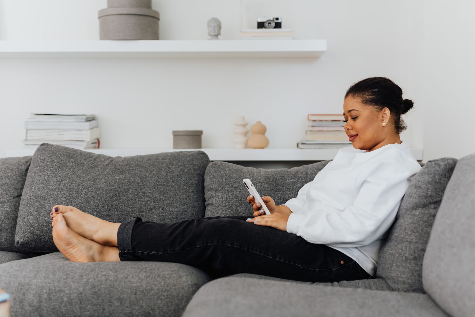 African guest using her phone while relaxing in a comfortable home