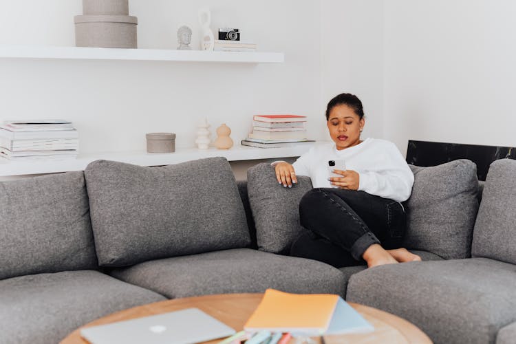 Woman Sitting On A Couch Scrolling Through Her Phone 