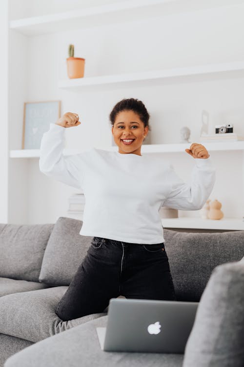 A Smiling Woman in White Sweater Kneeling on the Couch