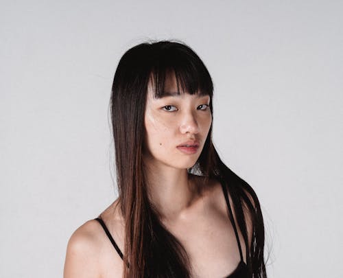 Attractive Asian woman with long hair against white wall