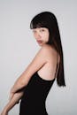 Charming Asian woman in black top standing against white background