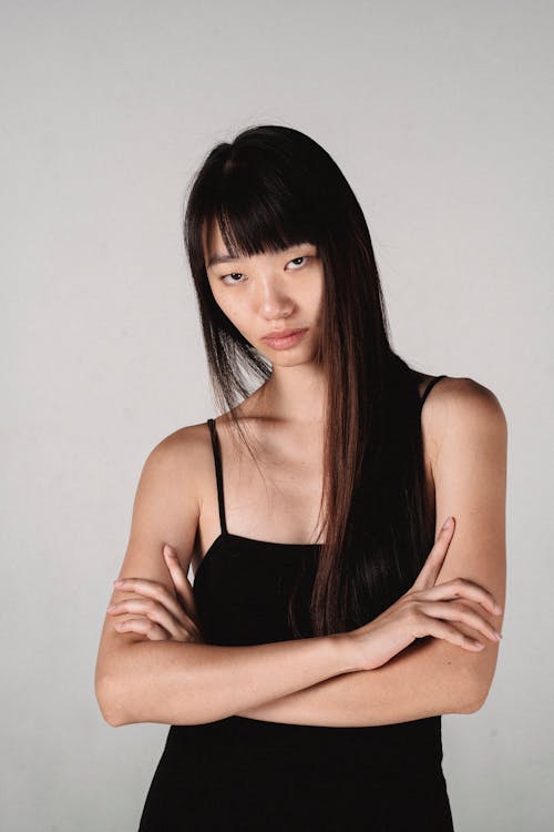 Arrogant Asian woman standing with arms crossed in studio