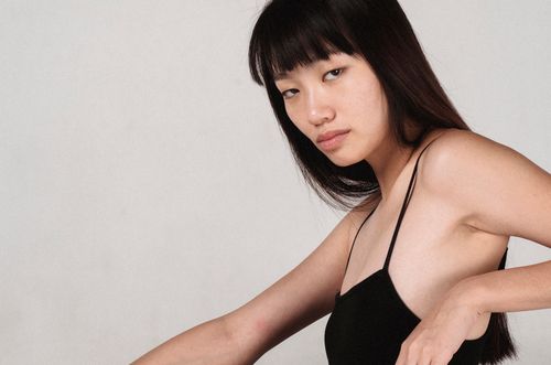 Free Side view of crop young sensual ethnic female with concentrated gaze looking at camera near wall Stock Photo