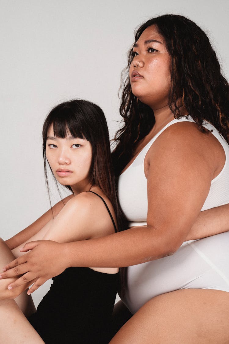 Calm Slender And Chunky Ethnic Women Cuddling In Studio