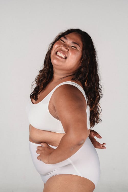 Happy young plump ethnic woman smiling with closed eyes in studio