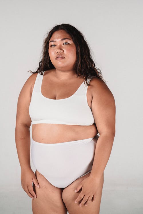 Plus size Asian female in white underwear looking at camera on white background