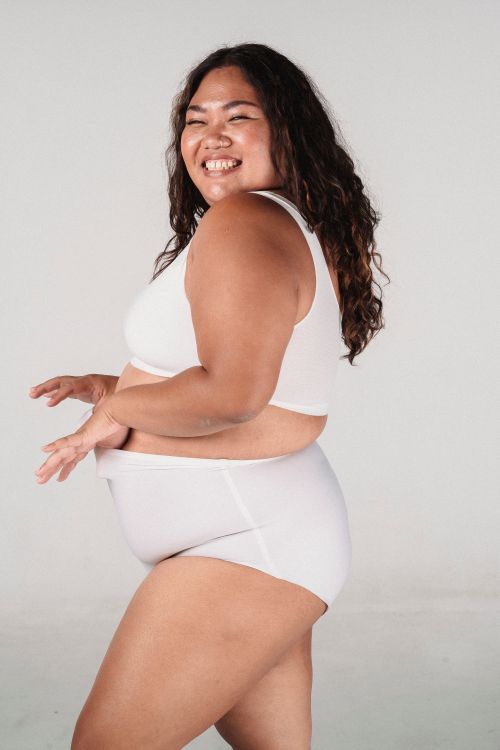 Free Side view of cheerful positive overweight Asian female with long curly hair on white background Stock Photo