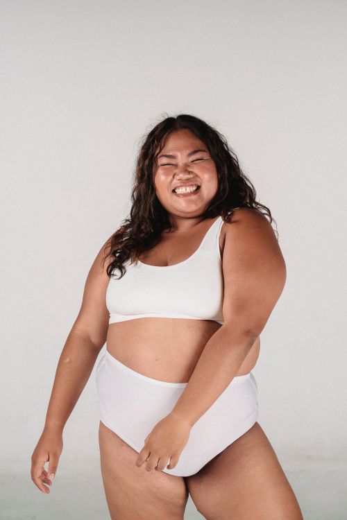Free Positive plus size tanned Asian female in underwear moving on white background of studio Stock Photo