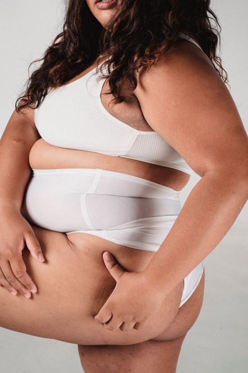Free Side view of anonymous crop plus size female in underwear touching buttocks on white background Stock Photo