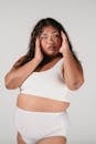 Young overweight Asian female with long hair touching face and looking away on white background