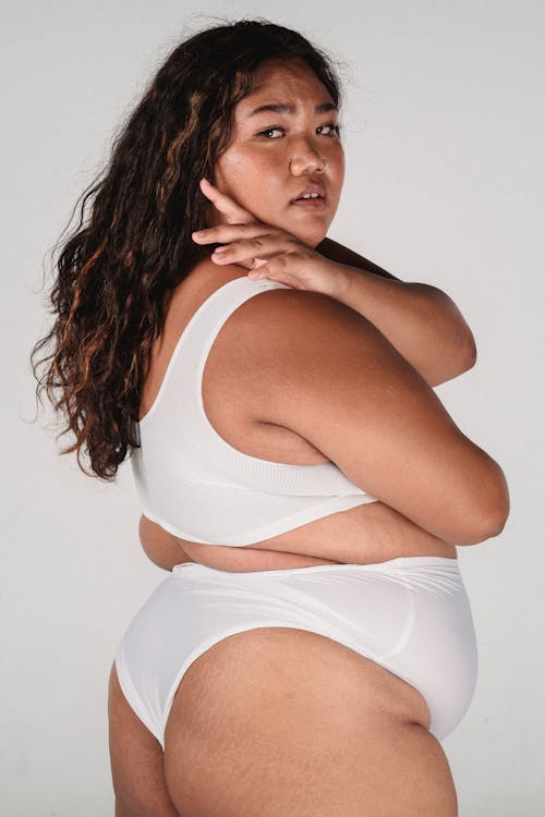 Free Plus size Asian female with long hair in underwear looking over shoulder on white background Stock Photo