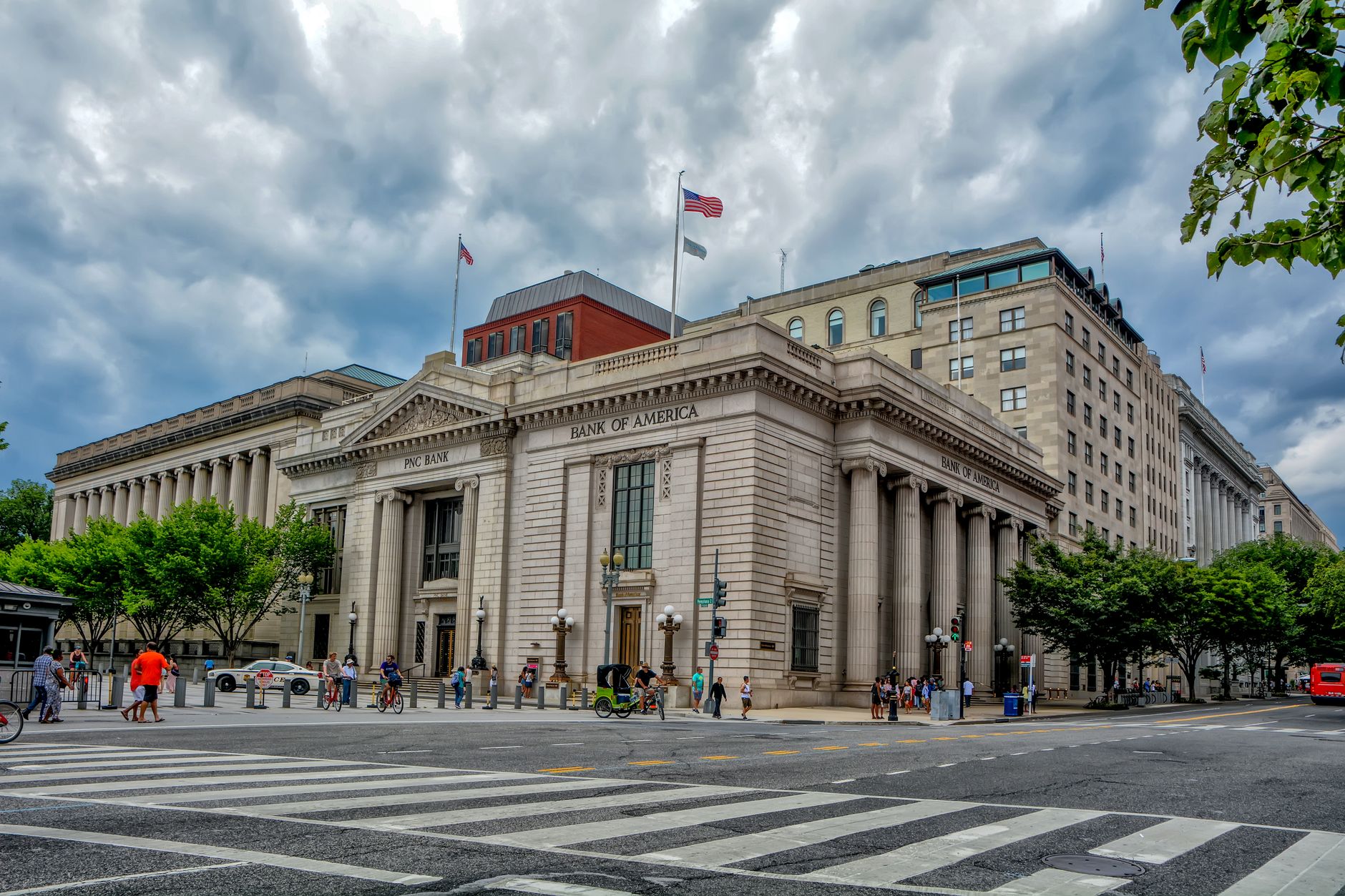 A classic architectural bank building under a dramatic sky in a bustling city environment.