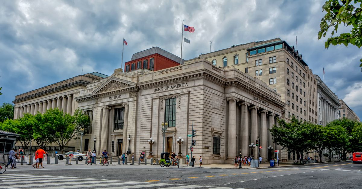 A classic architectural bank building under a dramatic sky in a bustling city environment.