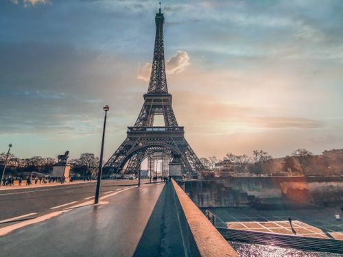 Free High metal tower near urban roadway on bridge over river under shiny cloudy sky at sundown Stock Photo