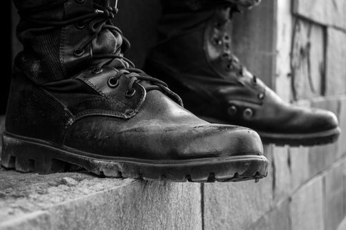 Free Close-up of black leather boots resting on a ledge in a monochrome setting. Stock Photo