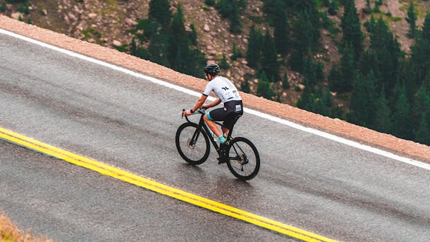 Cyclist riding up a mountainous road, showcasing fitness and adventure.