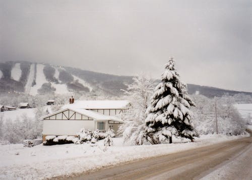House Covered with Snow Near a Dirt Road