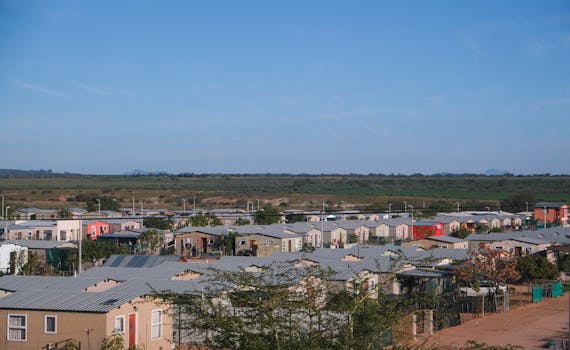 Drone shot of a small residential neighborhood with concrete houses on a clear day.