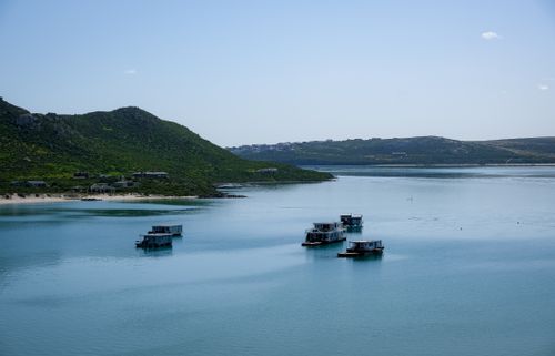 Free Peaceful lake scene with floating houses and green hills under a clear sky. Stock Photo