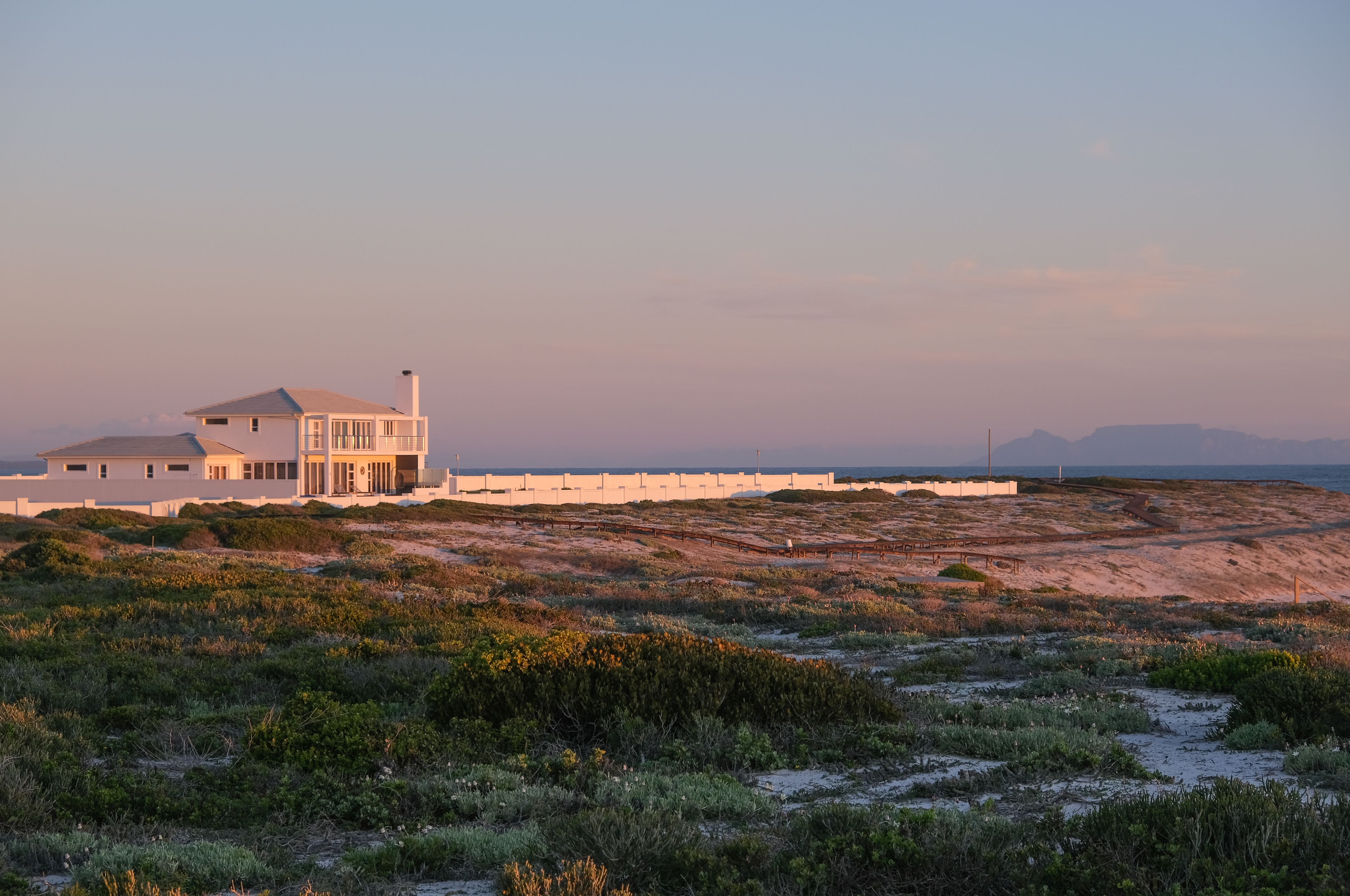 Beautiful coastal house in Yzerfontein, South Africa, at sunset with a tranquil seaside view.