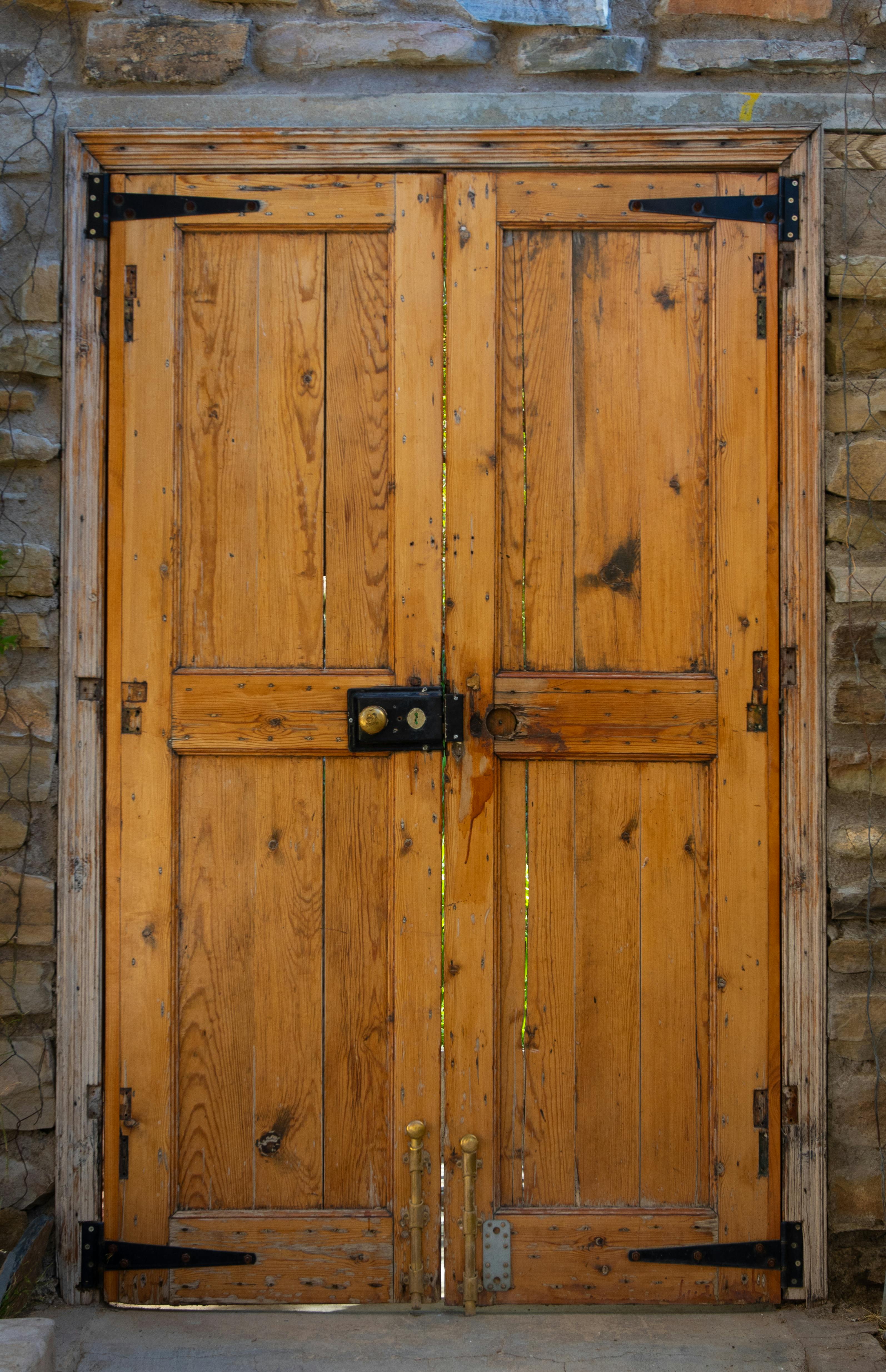 Close-up of a rustic wooden door with iron hinges set in a stone wall, exuding character and history.