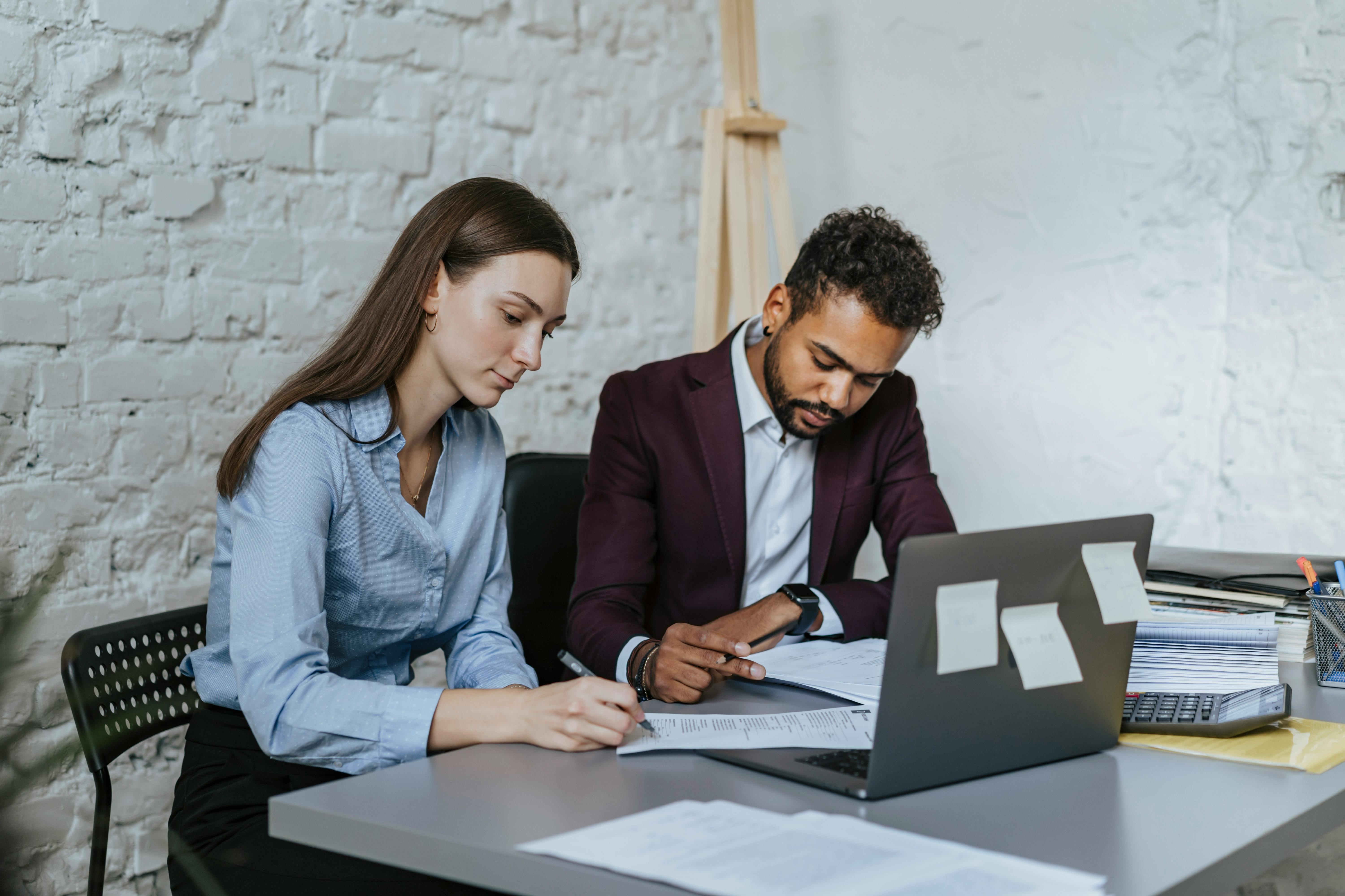 a man and a woman sitting at table while working