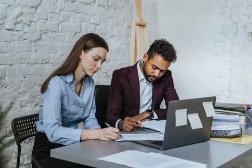 Free Two professionals working together at a desk in a modern office environment. Stock Photo