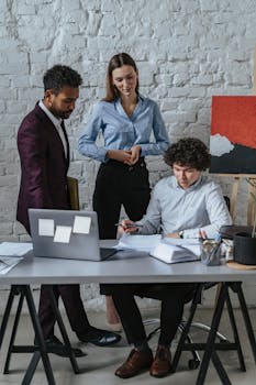 A diverse business team collaborates in a modern office setting, discussing documents and ideas.