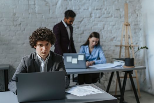 A diverse team working in a modern office setting with laptops and documents.