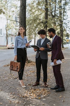 一群多元化的年轻专业人士在绿树成荫的人行道上讨论户外工作