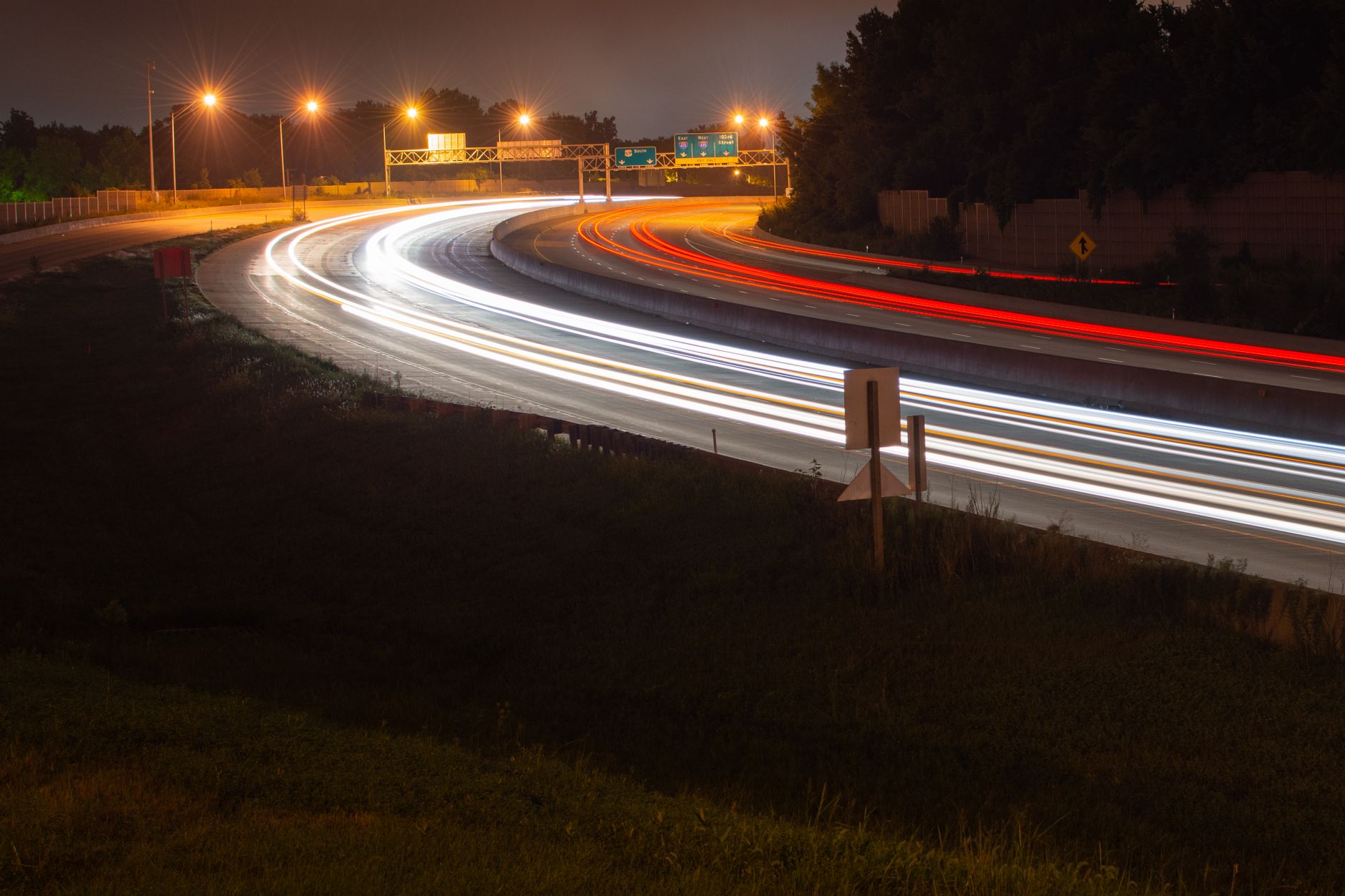Long exposure of light trails capturing fast-moving vehicles on a highway at night.