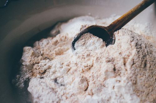 Free A close-up view of a wooden spoon resting in a mound of flour, perfect for baking themes. Stock Photo