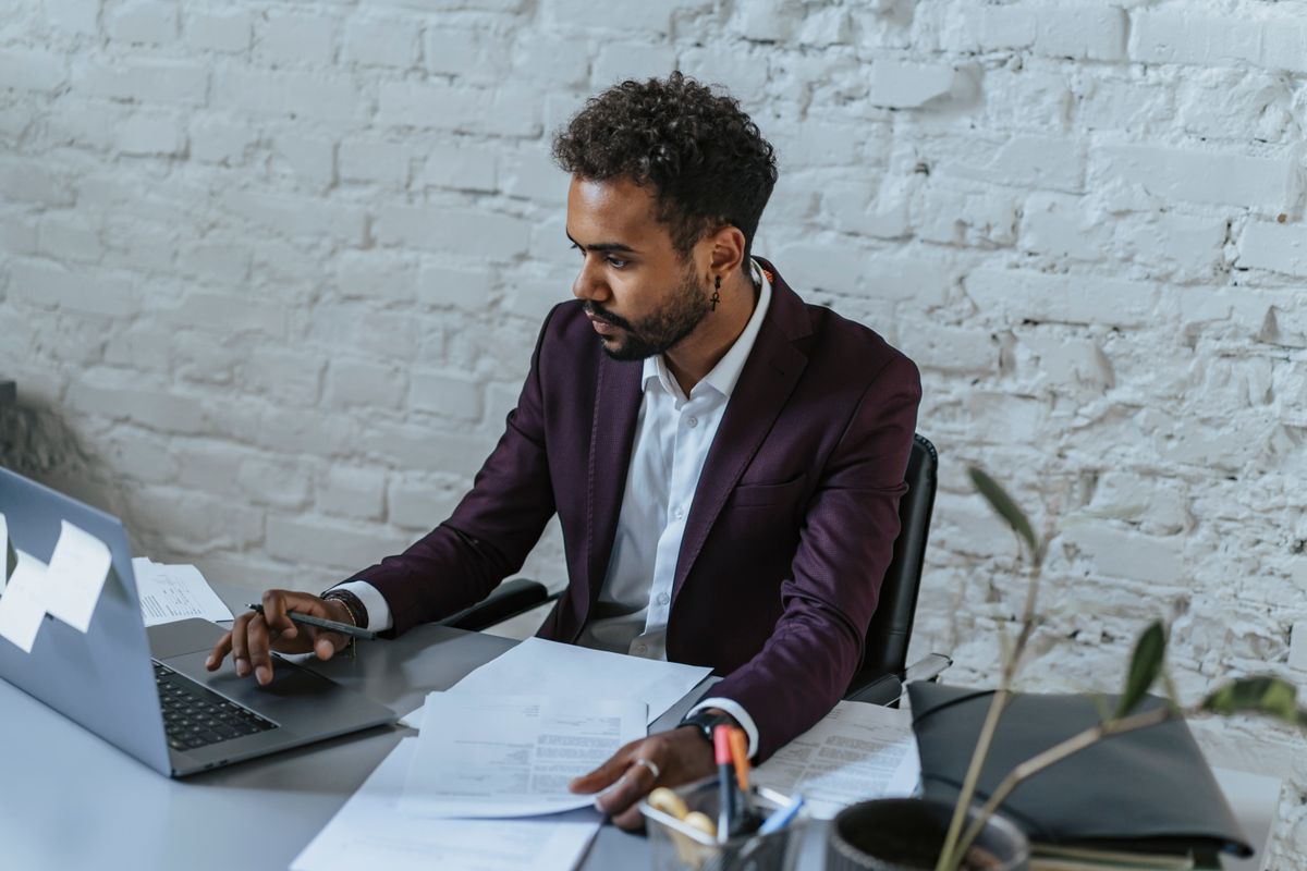 Person in a deliberate financial planning session reviewing documents and laptop at a desk