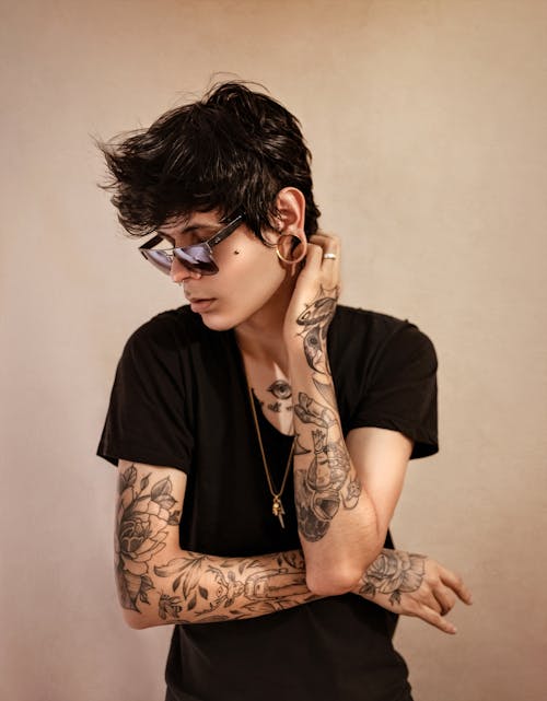 Tattooed androgynous model against beige background
