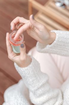 特写镜头聚焦于一个人从小容器中涂抹保湿霜的日常护肤动作