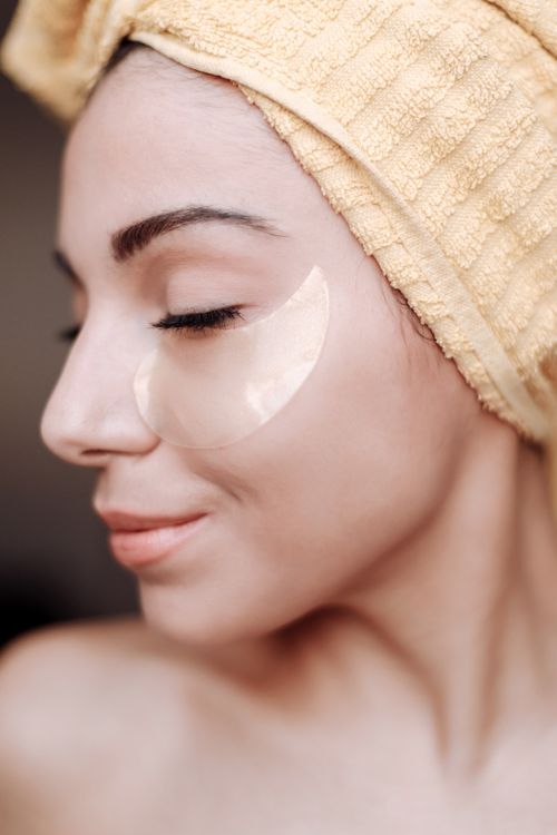 Free Profile of a woman with a towel on her head and under eye patch, emphasizing skincare. Stock Photo