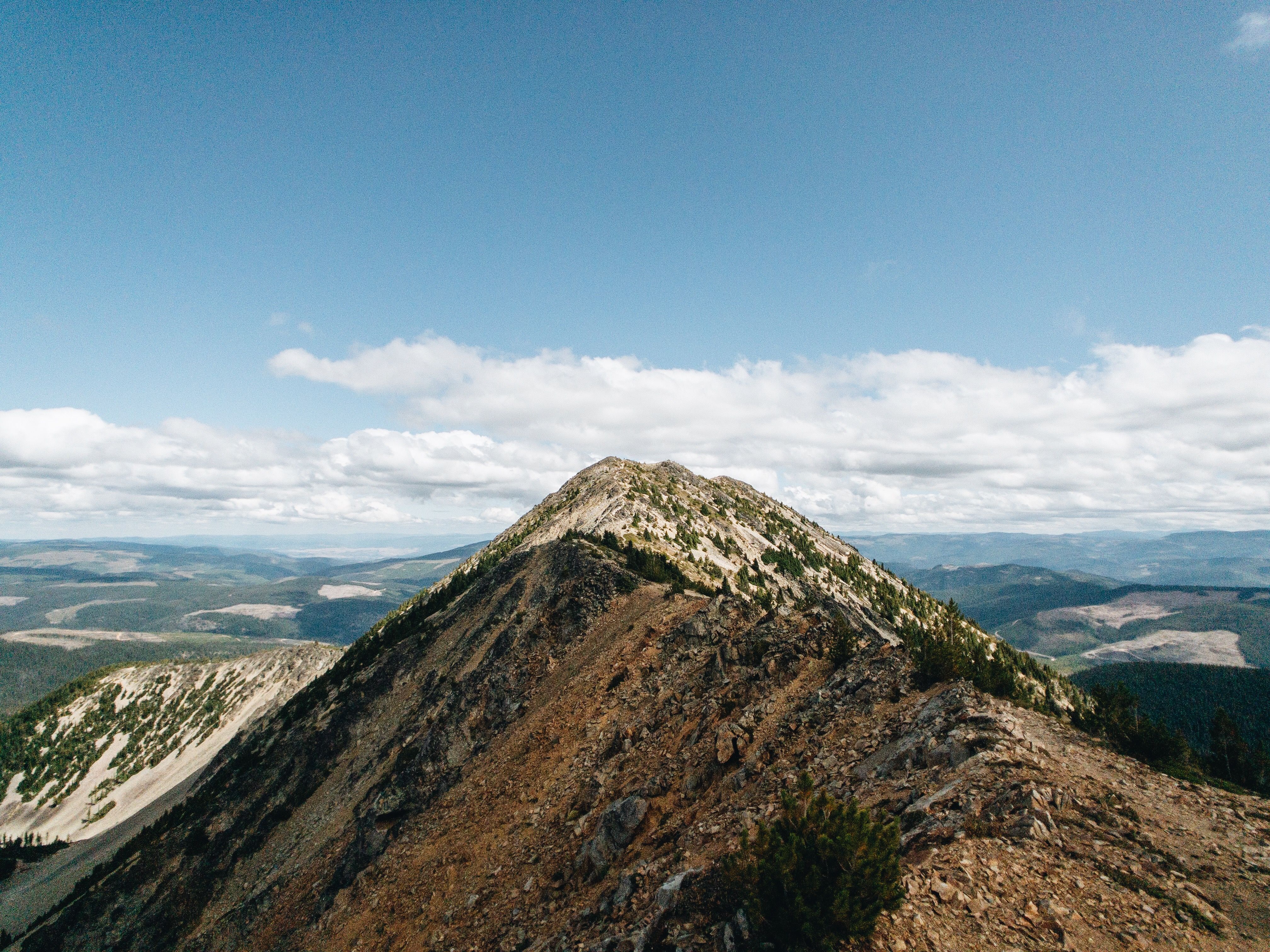 Breathtaking view of a mountain peak under a clear blue sky with white clouds, showcasing rugged landscape.