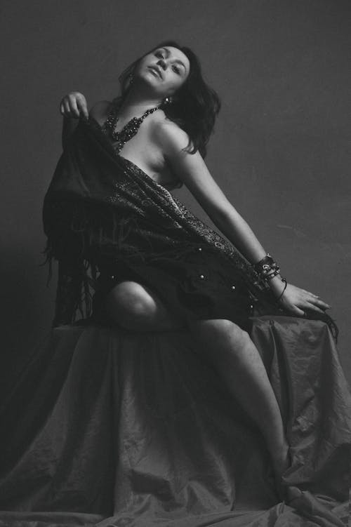 Grayscale Photo of Woman in Dress Sitting and Posing 