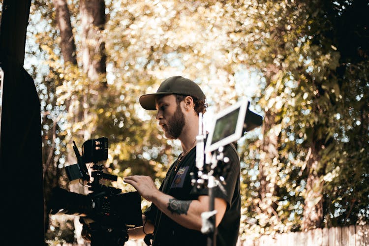 Man In Black Shirt And Cap Holding Camera 